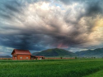 Scenic view of grassy field against cloudy sky