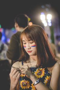 Smiling young woman standing outdoors at night