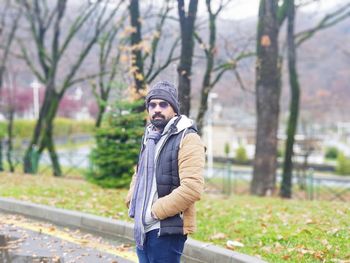 Young man standing by tree during winter