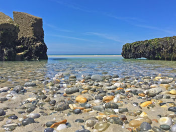 Rocks on beach against blue sky