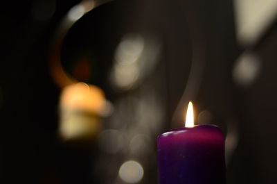 Close-up of lit candle in darkroom