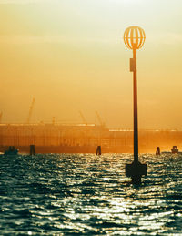 Silhouette people on sea against sky during sunset