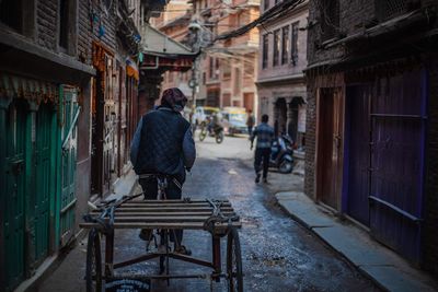 Rear view of man walking on street amidst buildings
