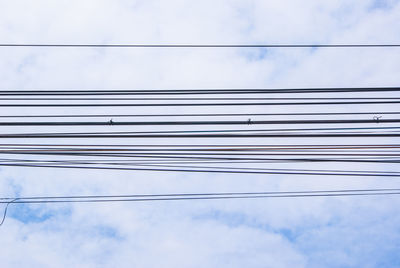 Low angle view of cables against cloudy sky