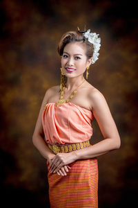 Portrait of female model smiling while standing against wall