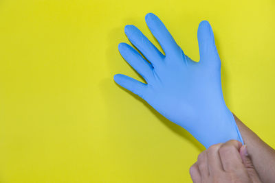 Close-up of hand holding yellow against blue background