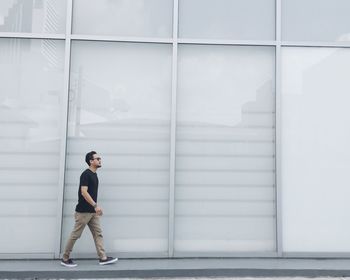 Side view of man walking on footpath by building
