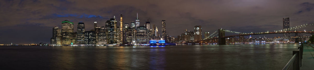 Illuminated bridge over river in city against sky at night