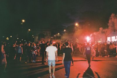 Group of people walking on street in city at night