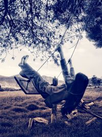 Side view of woman sitting on field against trees