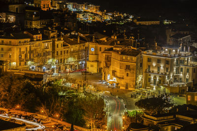 High angle view of illuminated street amidst buildings at night