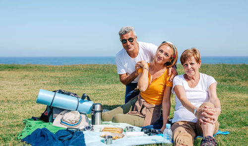 Adult family looking at camera sitting on a blanket having picnic