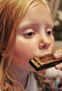 Close-up portrait of young woman looking away while playing harmonica 