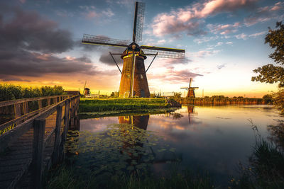 Reflection of traditional windmill in lake during sunset