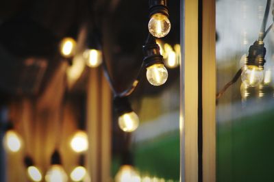 Close-up of illuminated light bulbs by window at home