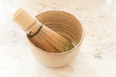 Close-up of wooden wire whisk in bowl on marble