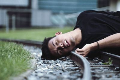 Young man sleeping on railroad track