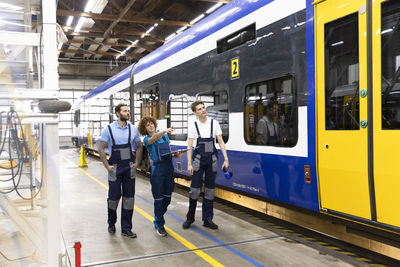 Engineer holding file discussing with colleagues by monorail at industry