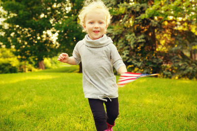 Portrait of girl holding american flag running on land