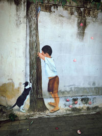 Full length of boy with birds on wall