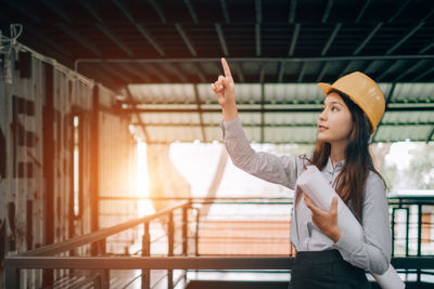 Young woman looking away while standing on railing