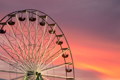 Low angle view of ferris wheel against sky at sunset