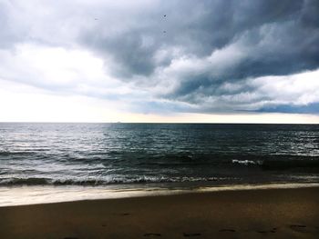 Scenic view of beach against cloudy sky