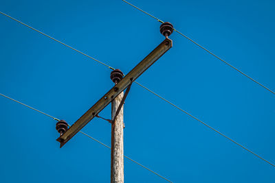 Low angle view of telephone pole against blue sky