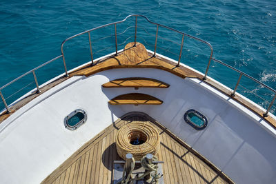 Bow of white yacht on background of blue sea. bay with thick rope lies on wooden deck.