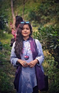 Happy young woman standing against trees