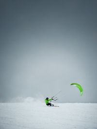 Man speed flying on snowy field against sky