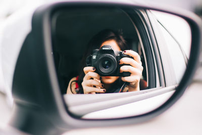 Reflection of man on side-view mirror of car