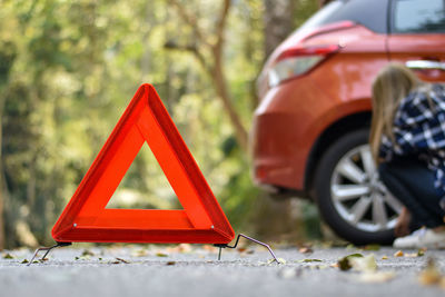 Close-up of red car on road against trees