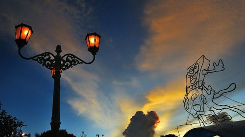 Low angle view of illuminated street light against sky at dusk