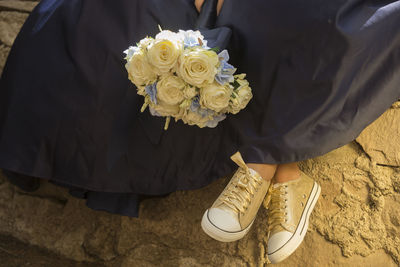 Golden tennis shoes, blue dress and a flower arrangement of white roses, fifteen year party concept