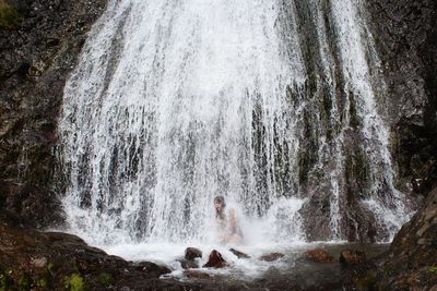 Woman enjoying in waterfall at forest
