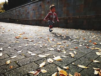 Boy running on footpath and leaves during autumn