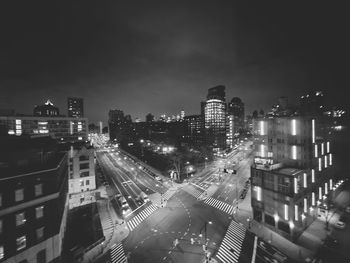 High angle view of illuminated street amidst buildings in city at night