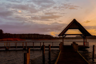 Wooden pier over lake against sky during sunset