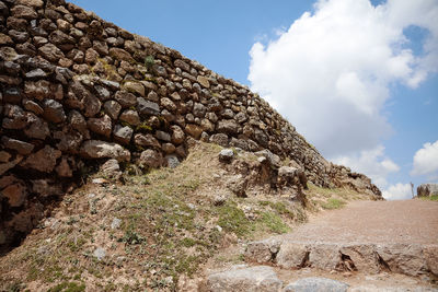 Low angle view of stone wall against sky