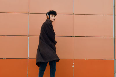Young woman standing against yellow wall