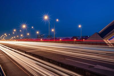 Light trails on highway against clear sky at night