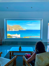 A man looking out of the window, watching the peace of a seaside