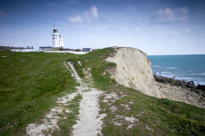 Lighthouse amidst sea and buildings against sky