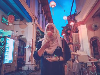 Woman standing at illuminated traditional clothing