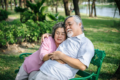 Senior couple sleeping on bench at park