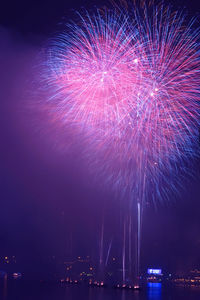 Low angle view of illuminated firework display against sky at night