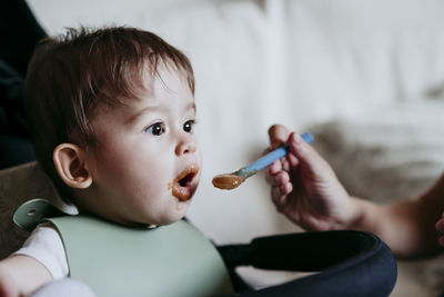 Mother's hand feeding baby boy at home