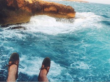 Low section of man sitting over sea