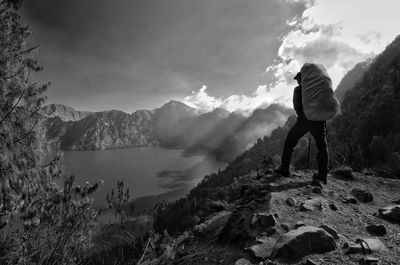 Rear view of man looking at mountains against sky